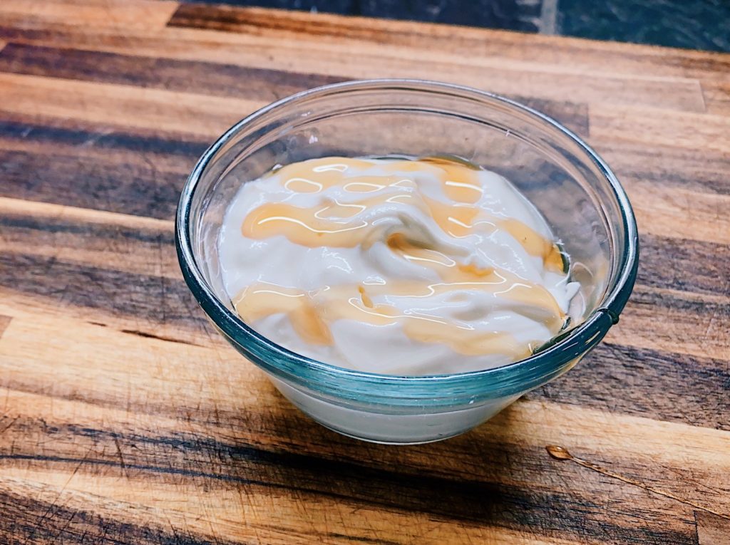 A bowl of creamy Greek Yogurt topped with golden honey